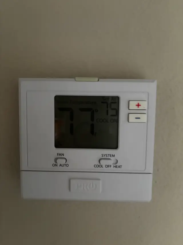 A Pro1 wall thermostat reading 77 degrees, set at 75, cooling on